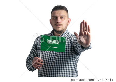 White guy holding a flag of Saudi Arabia and with a serious face shows a hand stop sign isolated on a white background White guy holding a flag of Saudi Arabia and with a serious face shows a hand stop sign isolated on a white background 78426814