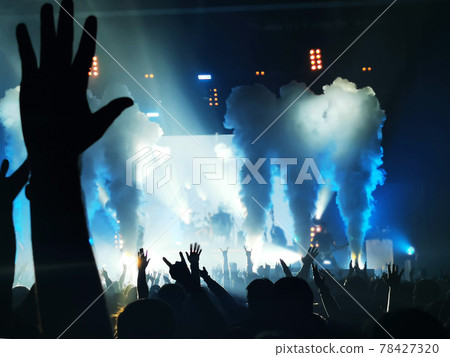 silhouettes of concert crowd in front of bright stage lights 78427320
