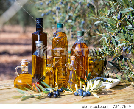 Olive oil on wooden table on background of olive tree 78427669