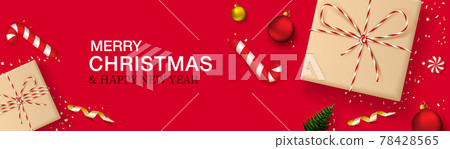 Merry Christmas and New Year horizontal banner. Red background with realistic gift boxes in craft paper, Christmas balls, christmas tree, candy and golden confetti. Header for website. 78428565
