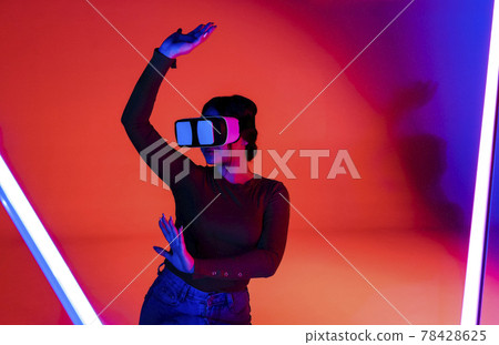 Cheerful woman in VR glasses under neon light Cheerful woman in VR glasses under neon light 78428625