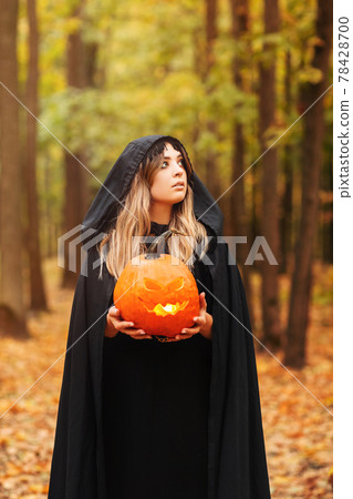 Young witch with jack o lantern in forest Young witch with jack o lantern in forest 78428700