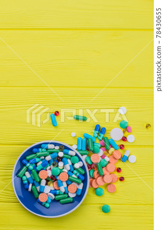 Heap of colored drugs on a tea plate. Heap of colored drugs on a tea plate. 78430655
