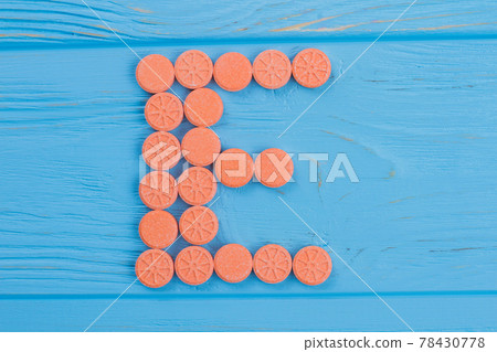 The letter E made of round orange drugs. 78430778
