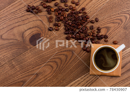 Topview cup of coffee and scattered coffee beans on wood. Topview cup of coffee and scattered coffee beans on wood. 78430907