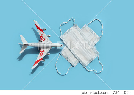 Top view or flat lay of airplane model and medical face mask on blue background. 78431001