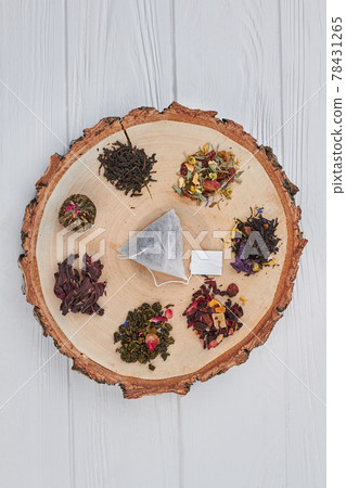 Wooden slice with dried assorted tea leaves. 78431265