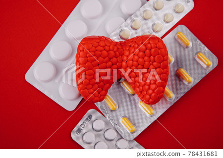 Plastic model of healthy thyroid and pills on red background close-up. Top view 78431681