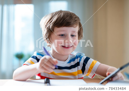 Back to school. Distance learning online education. Caucasian smile kid boy studying at home with smartphone and doing school homework. Smiling child siting at table with cell phone 78433484