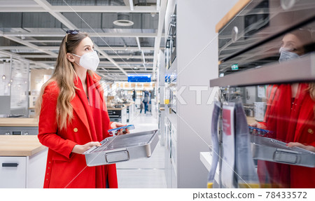 Woman looking for oven in kitchen store during pandemic with mask 78433572
