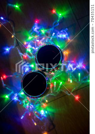 top view of glass wine glasses in shining christmas garland on dark background. top view of glass wine glasses in shining christmas garland on dark background. 78435151