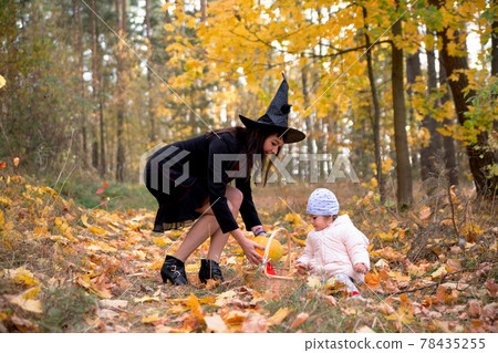 woman witch plays with a small child in the autumn forest. halloween concept costumes. witch and bunny. concept mother and daughter friends woman witch plays with a small child in the autumn forest. halloween concept costumes. witch and bunny. concept mother and daughter friends 78435255