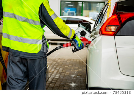 gas station employee in overalls refueling the car 78435318