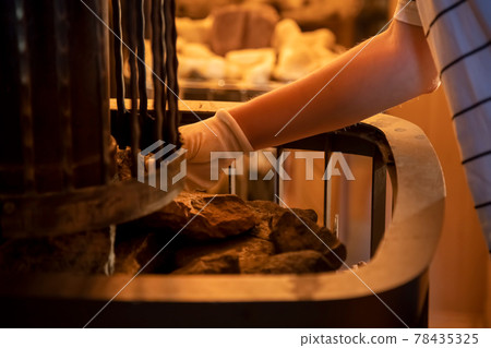 the hands of the master lay stones in the sauna stove 78435325