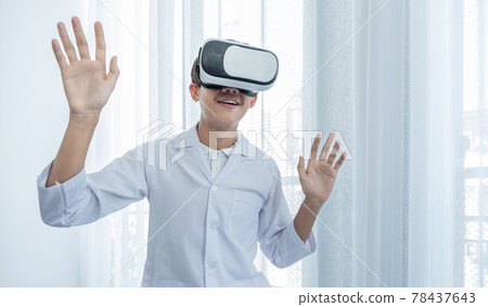 VR box. A young Asian man in a doctor's uniform makes an excited expression while learning VR box. A young Asian man in a doctor's uniform makes an excited expression while learning 78437643