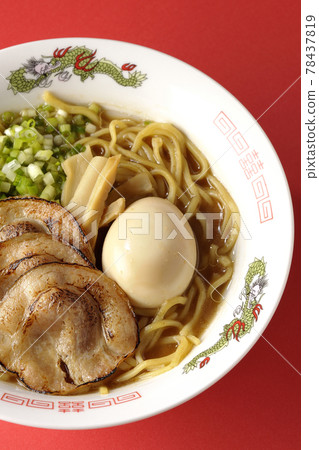 A bird's-eye view of pork bone soy sauce ramen containing roasted char siu, taste balls, menma and all-purpose green onions on a red background A bird's-eye view of pork bone soy sauce ramen containing roasted char siu, taste balls, menma and all-purpose green onions on a red background 78437819