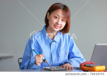 Female engineer who raised her face while fixing the solder on the board_front 78438745