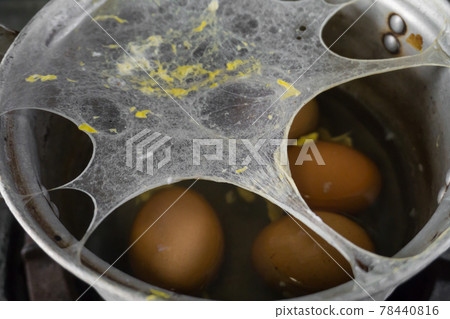 Exploding boiled eggs in a dirty pot on a dirty gas stove 78440816