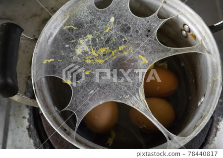 Exploding boiled eggs in a dirty pot on a dirty gas stove 78440817