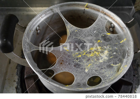 Exploding boiled eggs in a dirty pot on a dirty gas stove 78440818