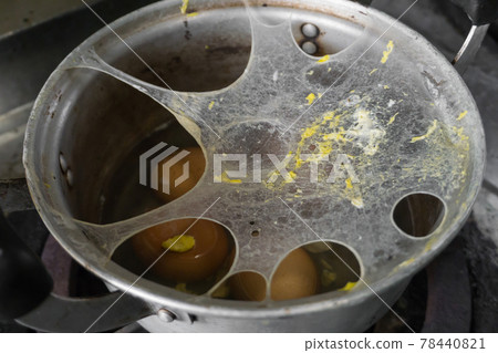 Exploding boiled eggs in a dirty pot on a dirty gas stove 78440821