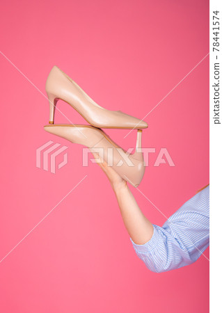 Women's shoes lie on a woman's hand. On a pink background Women's shoes lie on a woman's hand. On a pink background 78441574