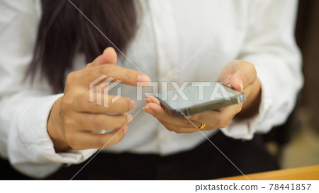 Cropped shot of female office worker using smartphone in her hands in workplace Cropped shot of female office worker using smartphone in her hands in workplace 78441857