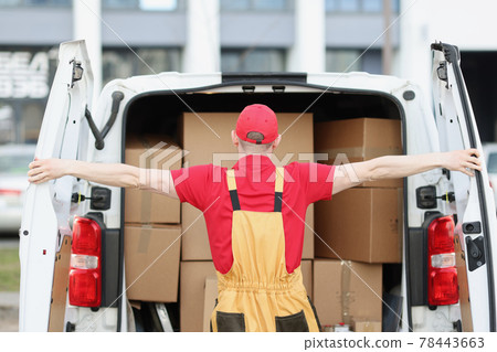 Male courier in uniform opening minivan with many cardboard boxes Male courier in uniform opening minivan with many cardboard boxes 78443663