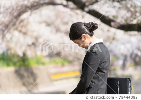 Even though it's spring, a young business woman feels depressed and worried on the riverbank lined with cherry blossom trees. Even though it's spring, a young business woman feels depressed and worried on the riverbank lined with cherry blossom trees. 78444082