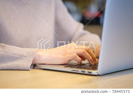 The girl in the cafe works at a laptop. 78445573