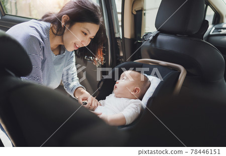 Asian young mother putting her baby son into car seat Asian young mother putting her baby son into car seat 78446151