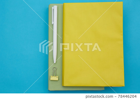 Top view of green and yellow book and white pen isolated on blue background Top view of green and yellow book and white pen isolated on blue background 78446204