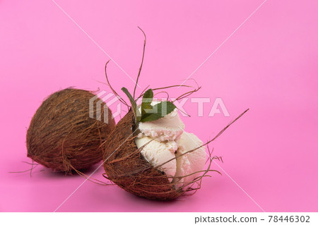 Vanilla ice cream balls in an empty coconut decorated with mint leaves on a pink background 78446302