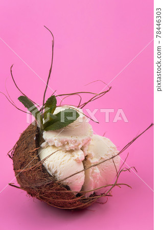 Vanilla ice cream balls in an empty coconut decorated with mint leaves on a pink background 78446303