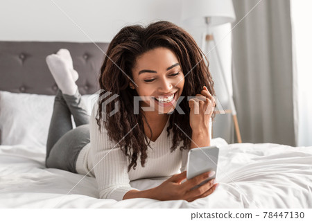 Happy black woman using phone shaking clenched fist 78447130