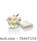 Transparent vase with water and white lilies with a white towel. Isolated on white. Spa concept for cleanliness, freshness and aromatherapy. 78447159