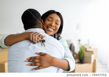 House ownership concept. Excited black woman holding house key and hugging her husband, free space 78447358