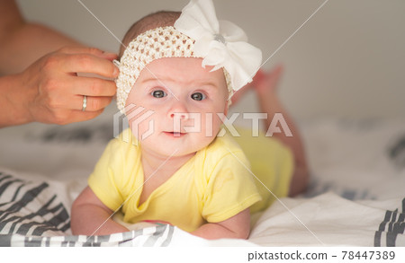 Cute baby portrait girl on bed in bright interior. 78447389