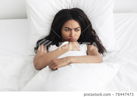 Bad morning sleep concept. Upset african american woman waking up and lying in bed, feeling angry Bad morning sleep concept. Upset african american woman waking up and lying in bed, feeling angry 78447473