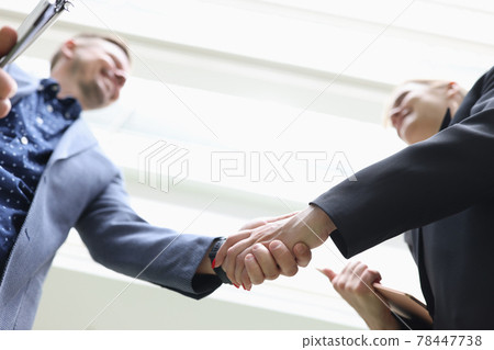 Smiling Businessman and businesswoman shake hands closeup 78447738