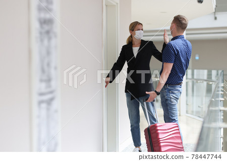 Woman and man give each other five, standing near door with suitcase 78447744