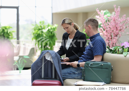 Man and woman in the hotel lobby looking at information on laptop Man and woman in the hotel lobby looking at information on laptop 78447786