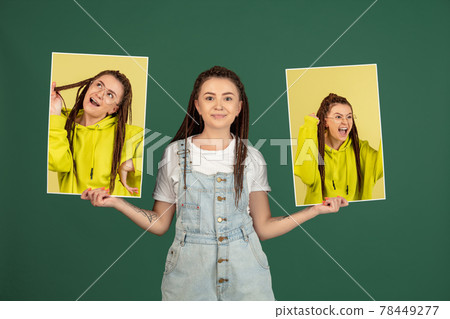 Young girl holding her portraits isolated over green studio background with copyspace for ad. Concept of beauty, fashion. 78449277