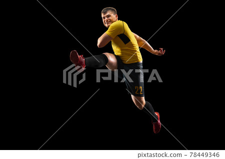 Powerful, flying above the field. Young football, soccer player in action, motion isolated on black background . 78449346