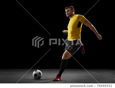 Powerful, flying above the field. Young football, soccer player in action, motion isolated on black studio background . Powerful, flying above the field. Young football, soccer player in action, motion isolated on black studio background . 78449352