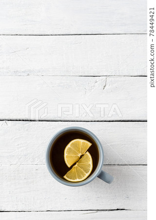 Mug of tea with lemon on white wooden background with copyspace. Flat lay 78449421