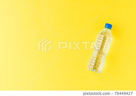 Overhead shot of plastic bottle with water on yellow table with copyspace. Flat lay 78449427