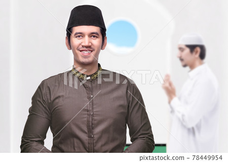 Asian Muslim man standing while raised hands and praying Asian Muslim man standing while raised hands and praying 78449954
