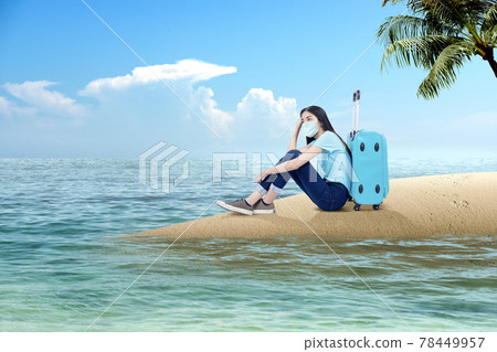 Asian woman with a face mask sitting with a suitcase on the beach Asian woman with a face mask sitting with a suitcase on the beach 78449957