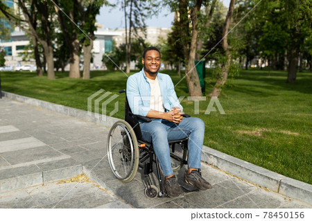 Accessible environment for disabled people concept. Happy black guy in wheelchair going down ramp on city street Accessible environment for disabled people concept. Happy black guy in wheelchair going down ramp on city street 78450156